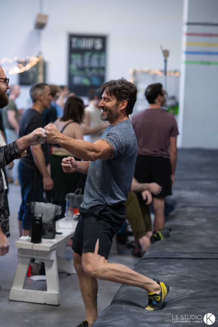 A fist bump between two climbers, the room behind them