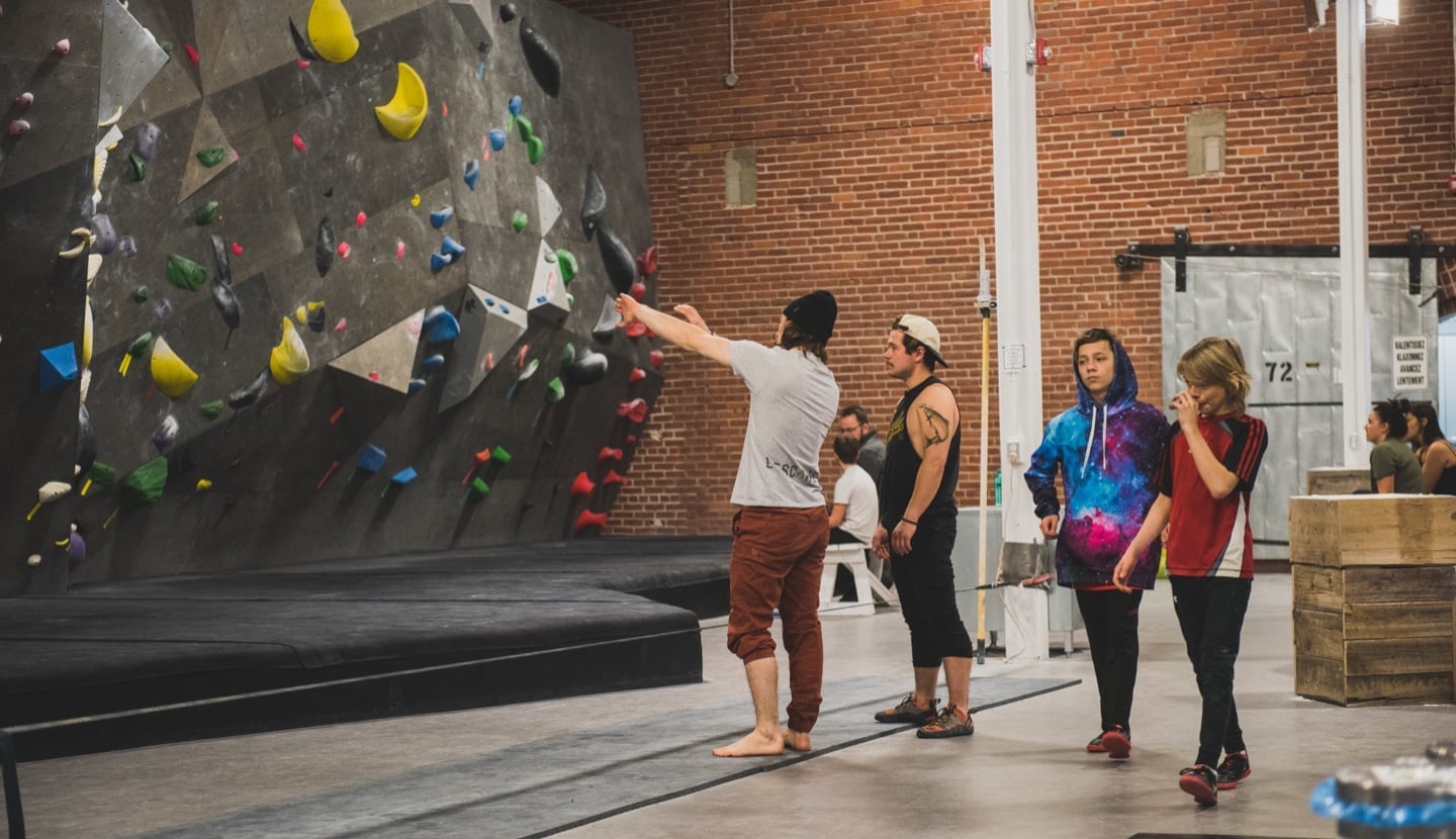 A coach points out a route to a small group in front of the wall.